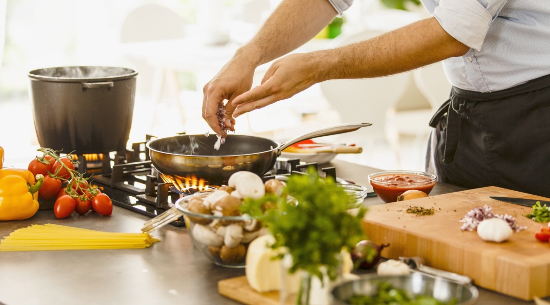 A chef prepares a delicious dish using fresh, colorful ingredients on a well-stocked kitchen counter.