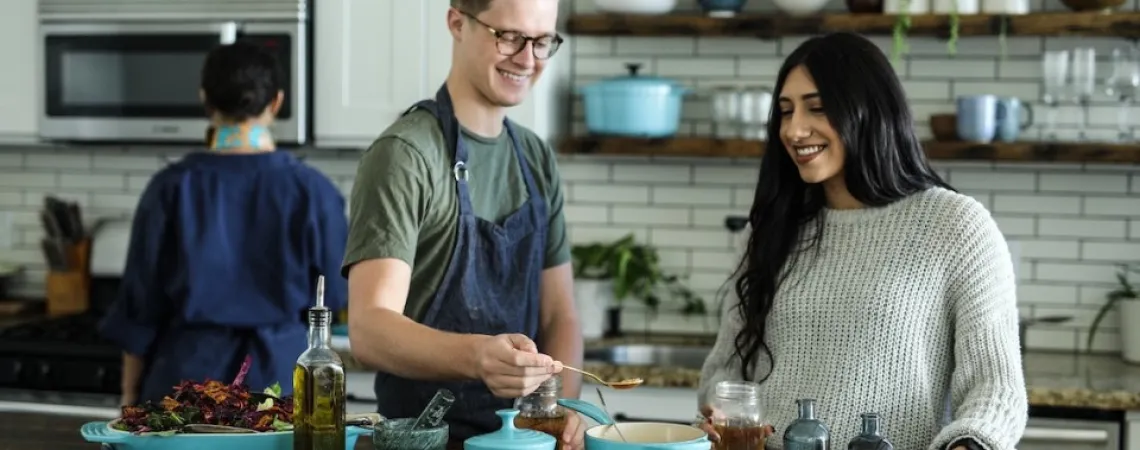 man and woman smiling as they cook