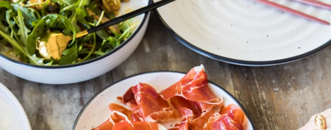 A plate of prosciutto and a plate of arugula