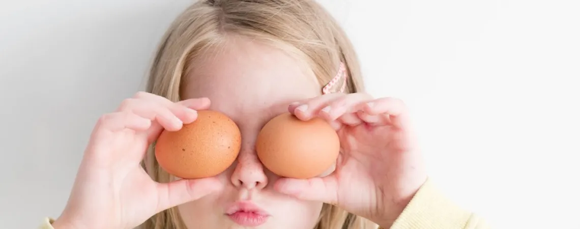 child hiding his eyes with eggs