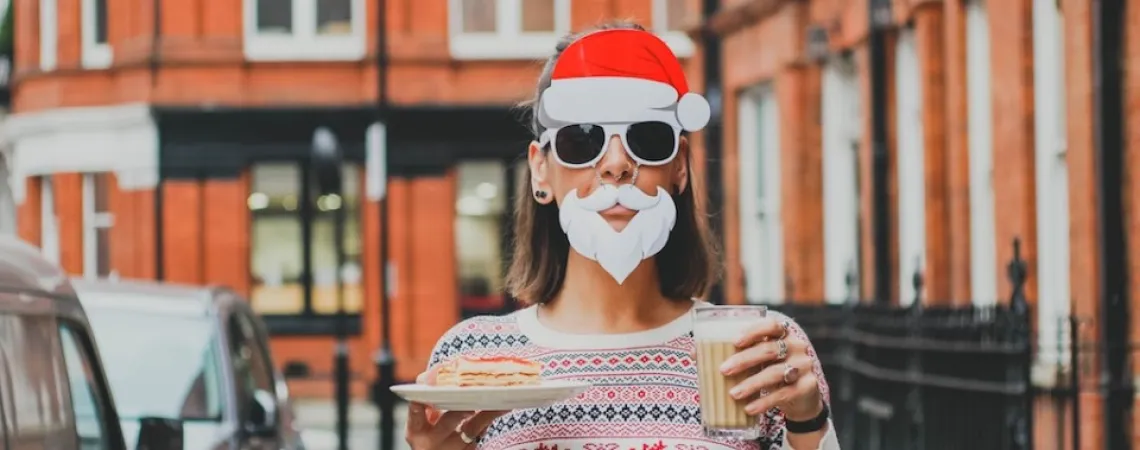 woman dressed as santa claus holding a glass of eggnog and a dessert