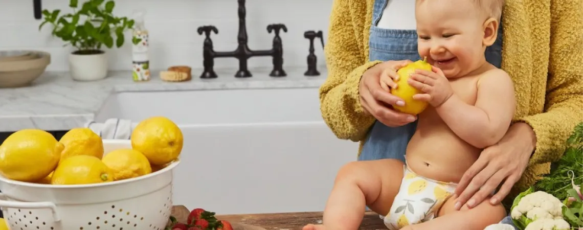 baby on the counter touching fruits