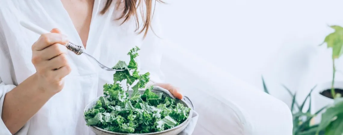 Girl dressed in white eating a kale salad
