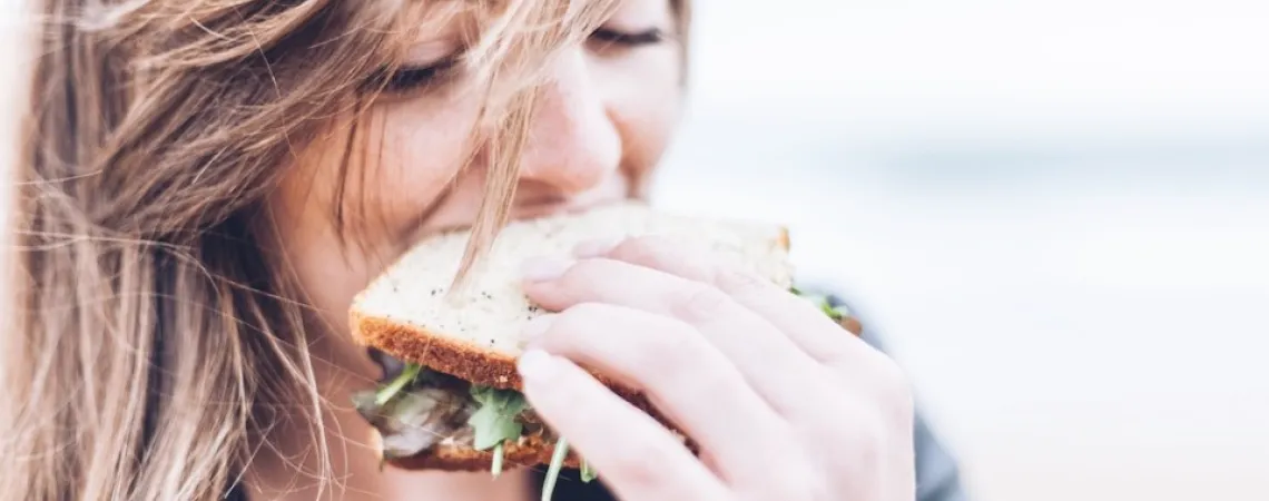 Girl eating a sandwich with wind blowing her hair