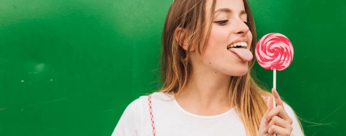 girl with a white t-shirt licking a candy, green background