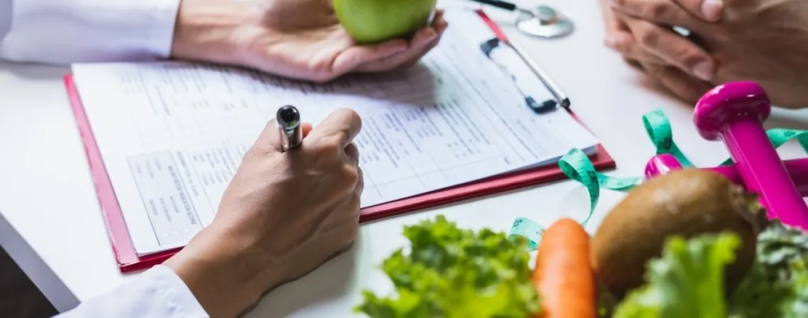 Toronto Dietitian Nutritionnist near you holding an apple and taking notes while talking to her client