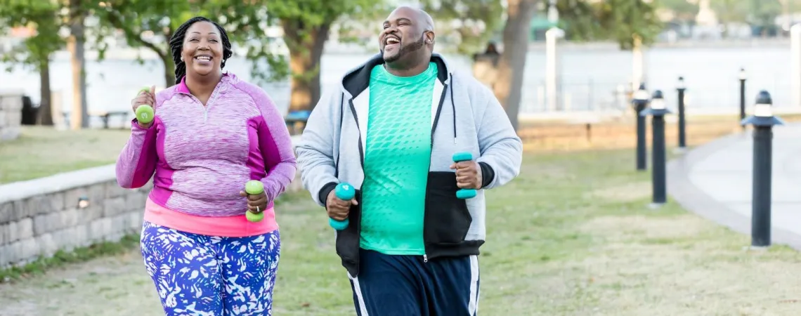 A smiling plus size couple jogs outdoors - Un couple en surpoids souriant fait du jogging en extérieur