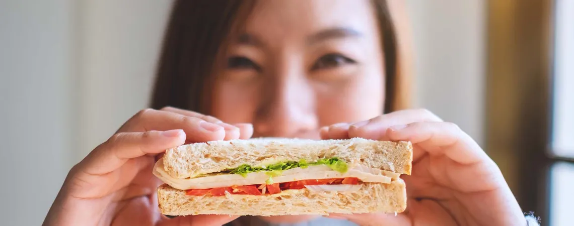 A smiling woman holding a sandwich - Une femme souriante tenant un sandwich