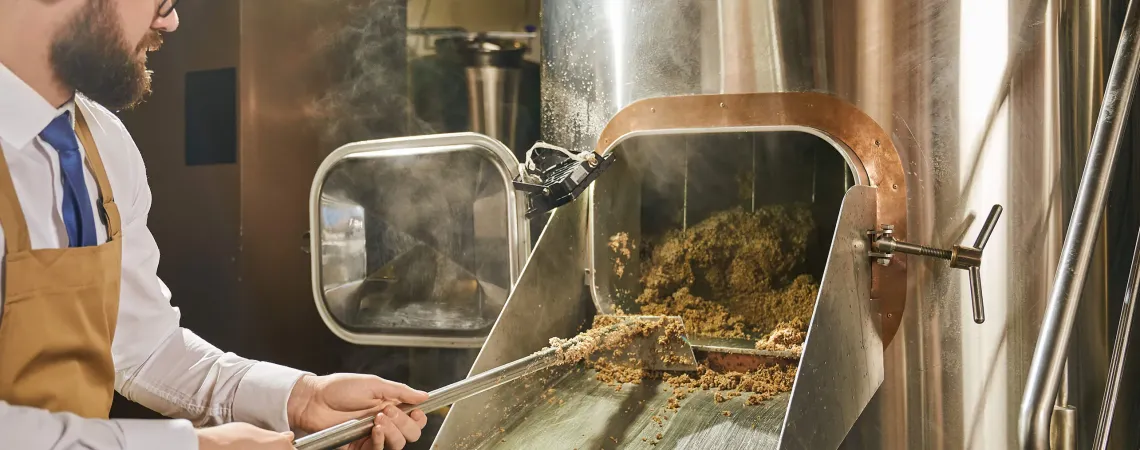 man taking the spent grains out of the brewing system