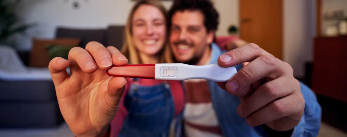 Couple heureux sourit en tenant un test de grossesse positif - Happy couple smiling and holding a positive pregnancy test