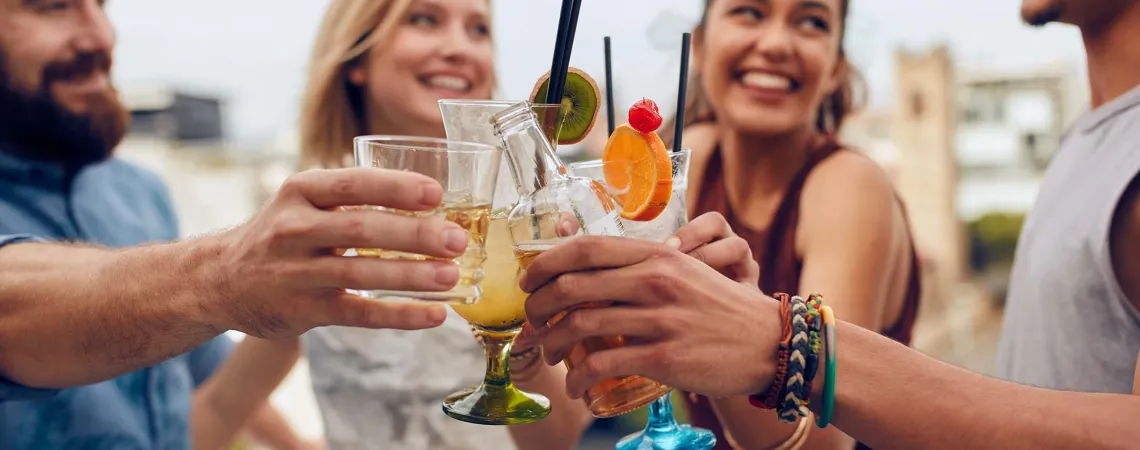 Des amis trinquent avec des cocktails lors d'une fête en plein air - Friends toasting with cocktails at an outdoor party
