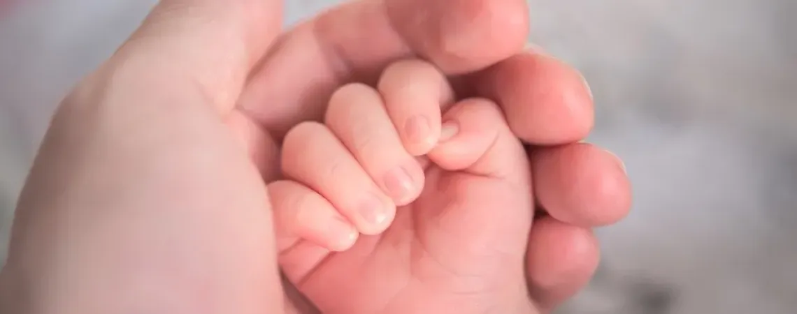 Hand of a baby in the hand of her mother