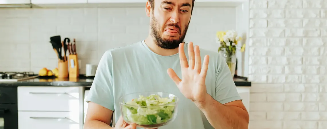 Homme faisant la grimace en tenant un bol de salade - Man grimacing while holding a bowl of salad