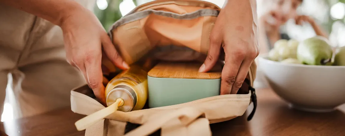Personne en train de préparer un sac avec une boîte à lunch et une bouteille - Person packing a bag with a lunchbox and a bottle