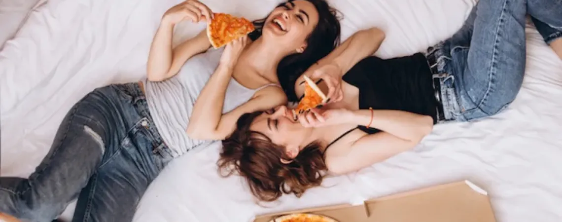 femmes qui mangent de la pizza sur le lit