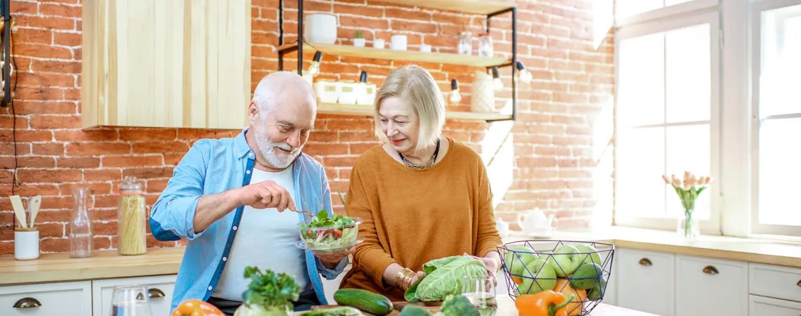 Couple senior préparant une salade ensemble dans une cuisine avec des légumes frais - Senior couple preparing a salad together in a kitchen with fresh vegetables