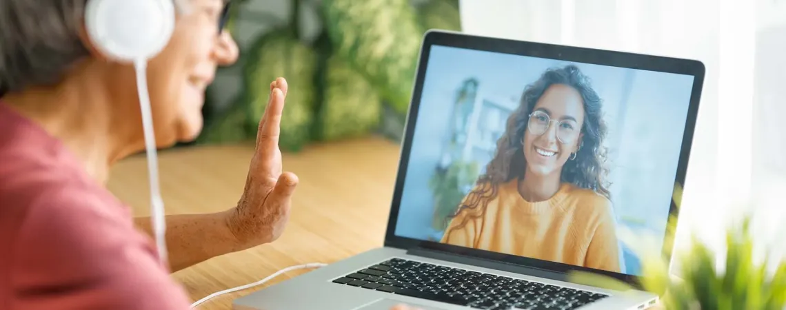 Older woman with headphones waving during a video call - Femme âgée avec des écouteurs faisant signe de la main pendant un appel vidéo