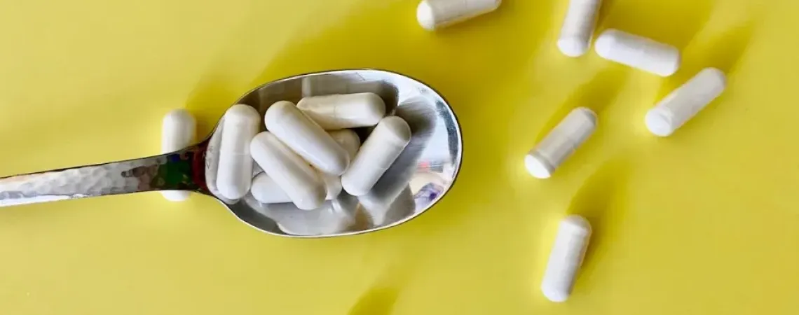 Supplements in a spoon on a yellow background