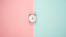 clock in the middle of a background pink and turquoise