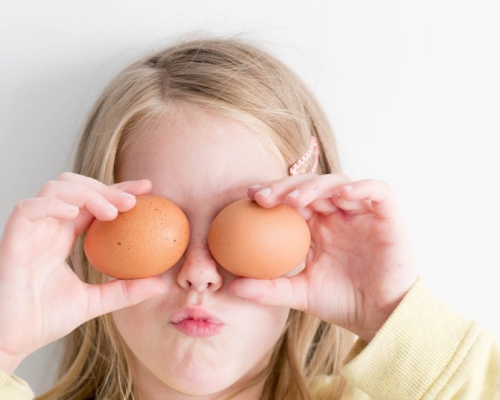 child hiding his eyes with eggs