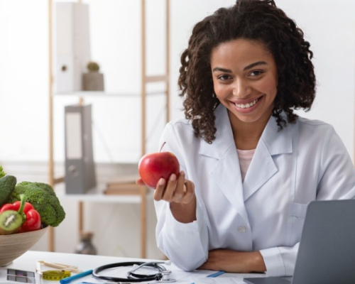 nutritionist-dietitian in her office presenting a fruit