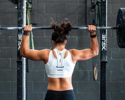 woman with muscular back lifting a dumbbell