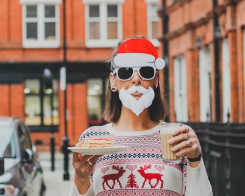 woman dressed as santa claus holding a glass of eggnog and a dessert