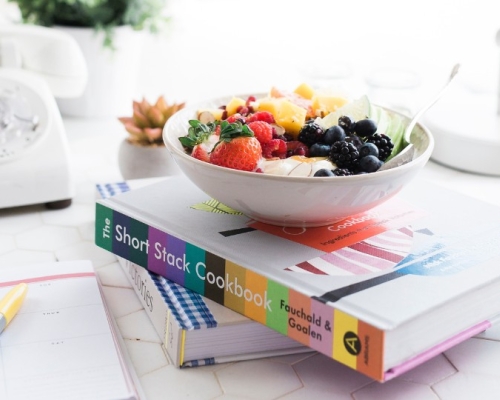 bowl of fruit on a pile of books