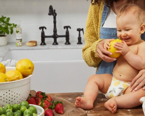 baby on the counter touching fruits