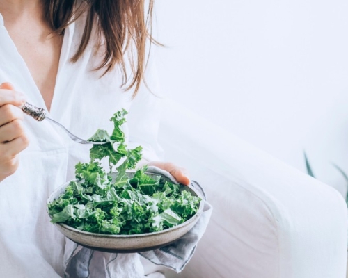 Girl dressed in white eating a kale salad