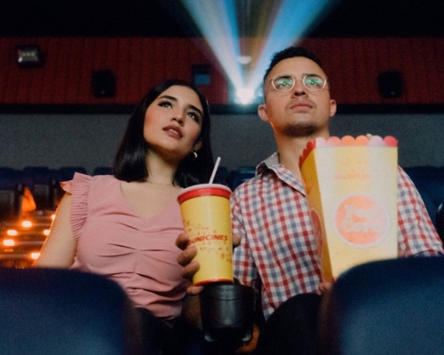 couple qui mange du popcorn avec des boissons gazeuses en écoutant un film au cinéma