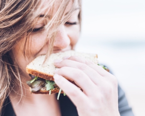 Girl eating a sandwich with wind blowing her hair