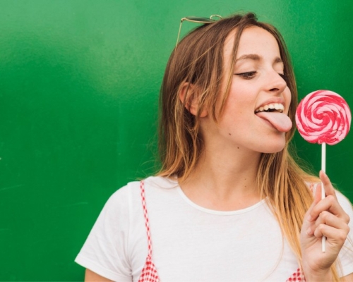 girl with a white t-shirt licking a candy, green background