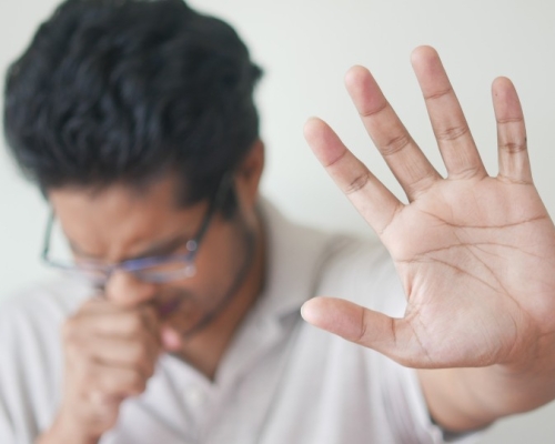 man in white sweater putting his hand in front of him