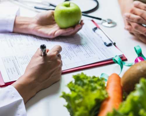 Toronto Dietitian Nutritionnist near you holding an apple and taking notes while talking to her client