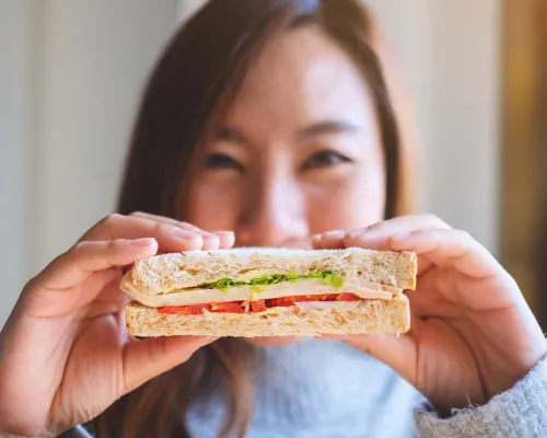 A smiling woman holding a sandwich - Une femme souriante tenant un sandwich