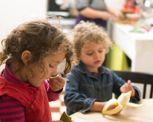 two little girls tasting fruit