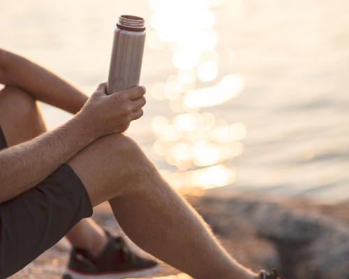 sportsman on the water's edge with his water bottle