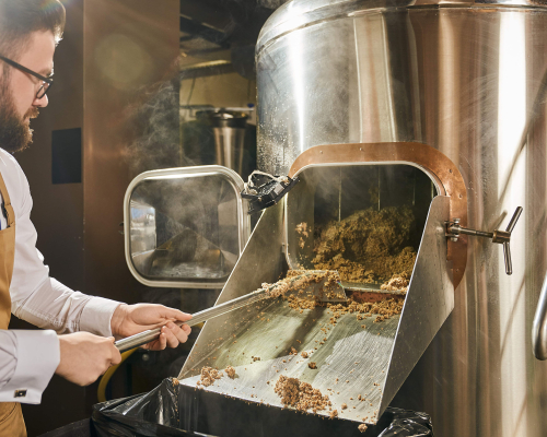 man taking the spent grains out of the brewing system