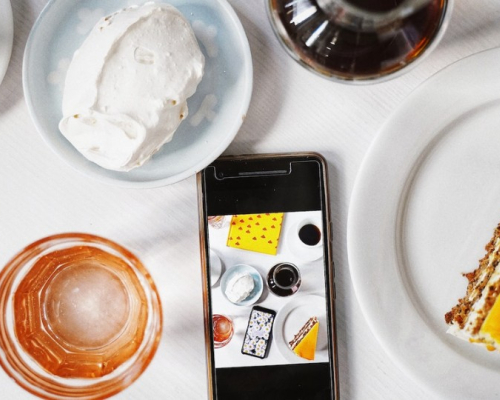 A cellphone  surrounded by food and drinks