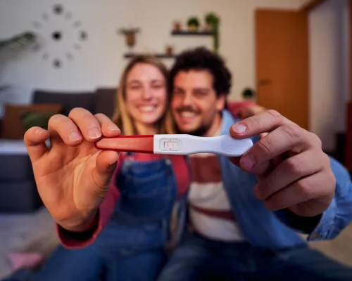 Couple heureux sourit en tenant un test de grossesse positif - Happy couple smiling and holding a positive pregnancy test