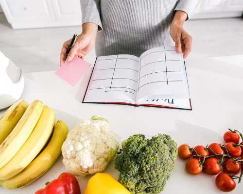 Cropped view woman near notebook with meal plan - Vue coupée d'une femme avec un carnet de note