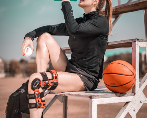 Woman sitting in the bleachers rinsing her mouth during physical activity