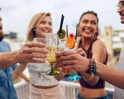 Des amis trinquent avec des cocktails lors d'une fête en plein air - Friends toasting with cocktails at an outdoor party
