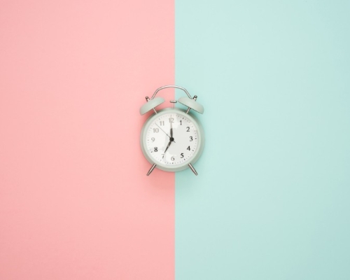 clock in the middle of a background pink and turquoise