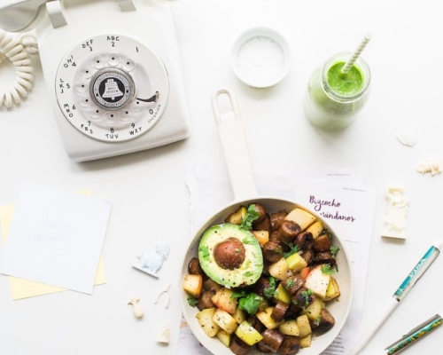 poêlée de légumes, smoothie et un téléphone sur une table blanche