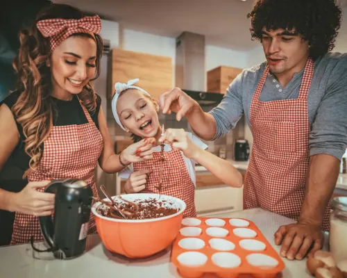 Famille souriante en train de cuisiner un dessert - Smiling family cooking a dessert together