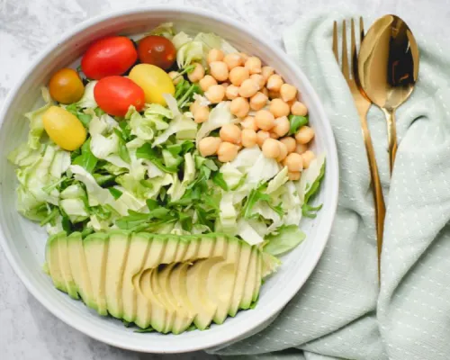 un bol de salade avec avocat, tomates et pois chiches