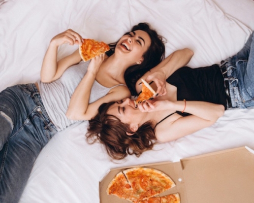 femmes qui mangent de la pizza sur le lit