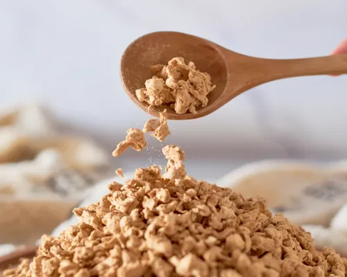 Cuillère en bois versant des protéines végétales texturées séchées - Wooden spoon pouring dried textured vegetable protein